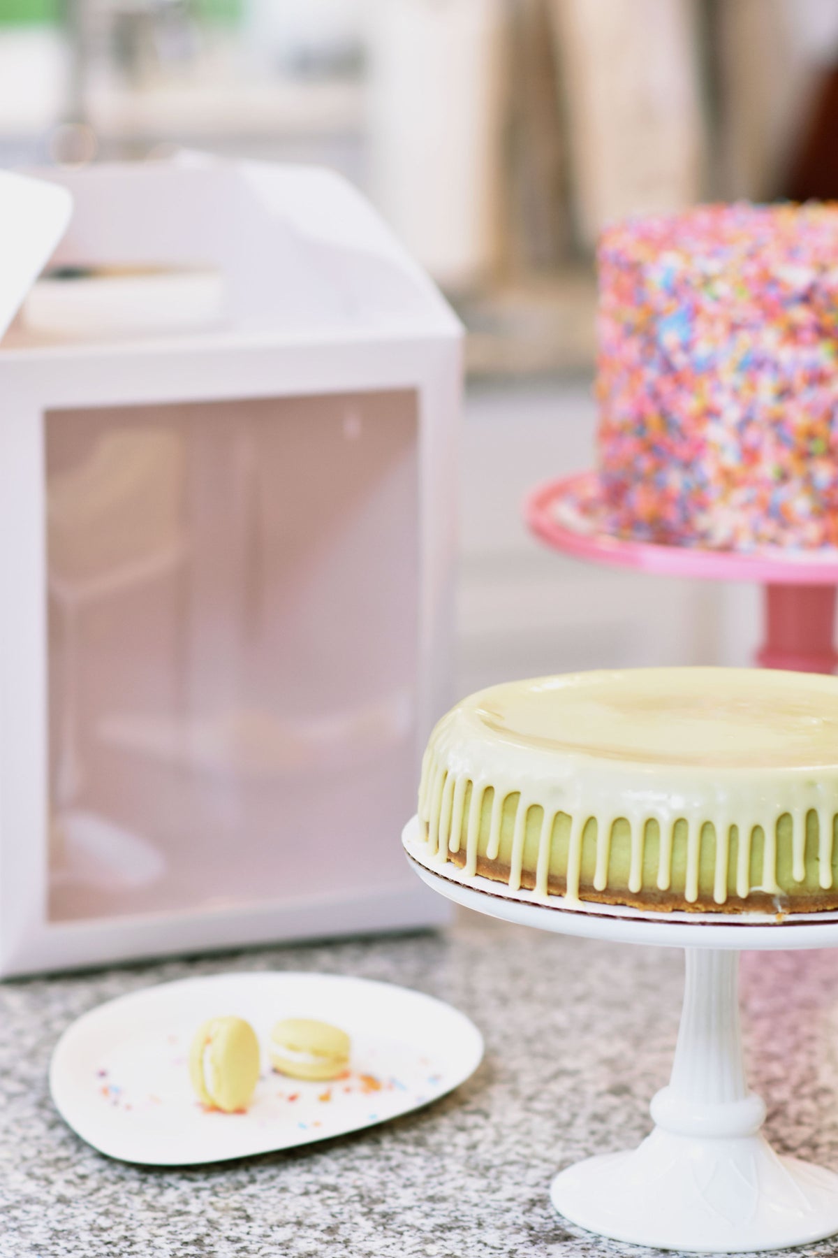 A tall cake in a 10x10x12 white paper cake box at a party